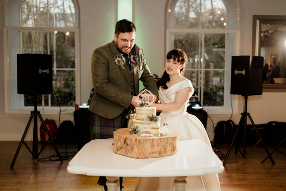 Bride and groom cut two-tier cake at The Venue, Eskmills